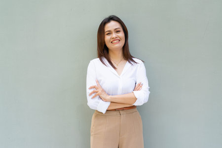 Portrait of beautiful Asian businesswoman against plain wall backgroundの写真素材