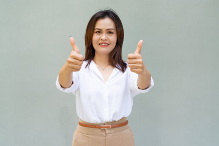 Portrait of beautiful Asian businesswoman against plain wall backgroundの写真素材