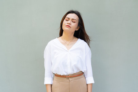 Portrait of beautiful Asian businesswoman against plain wall backgroundの写真素材