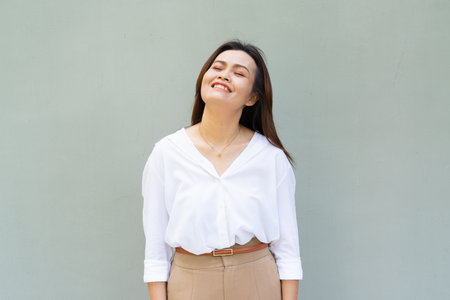 Portrait of beautiful Asian businesswoman against plain wall backgroundの写真素材