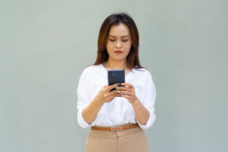 Portrait of beautiful Asian businesswoman against plain wall backgroundの写真素材