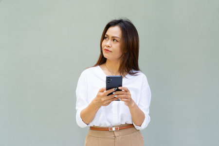 Portrait of beautiful Asian businesswoman against plain wall backgroundの写真素材