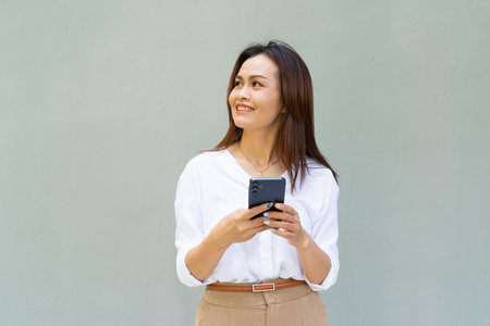 Portrait of beautiful Asian businesswoman against plain wall backgroundの写真素材