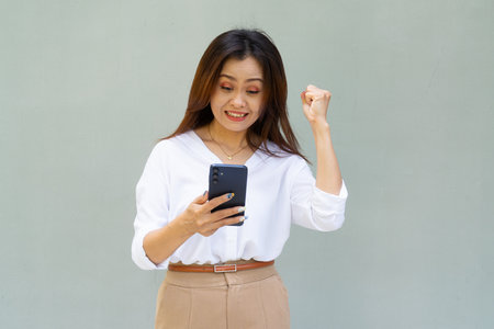 Portrait of beautiful Asian businesswoman against plain wall backgroundの写真素材