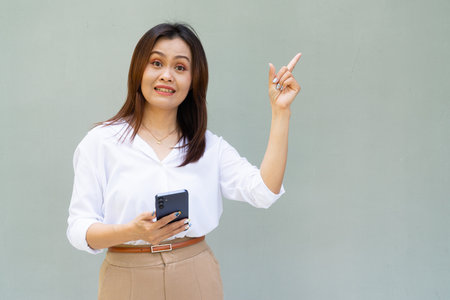 Portrait of beautiful Asian businesswoman against plain wall backgroundの写真素材