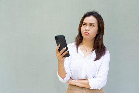 Portrait of beautiful Asian businesswoman against plain wall backgroundの写真素材
