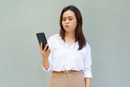 Portrait of beautiful Asian businesswoman against plain wall backgroundの写真素材