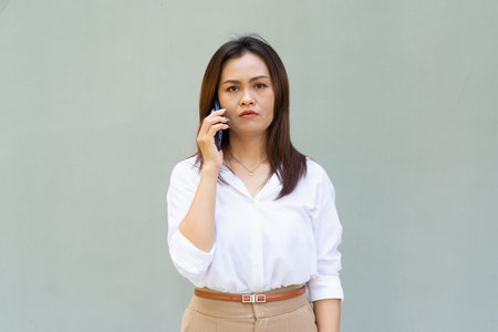 Portrait of beautiful Asian businesswoman against plain wall backgroundの写真素材