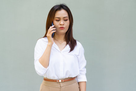 Portrait of beautiful Asian businesswoman against plain wall backgroundの写真素材