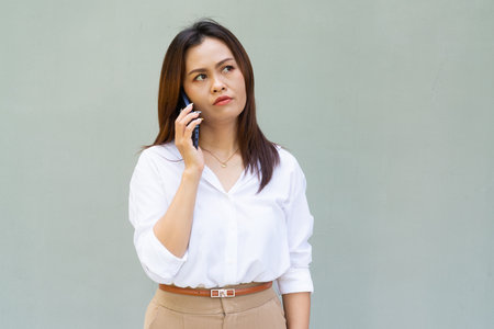 Portrait of beautiful Asian businesswoman against plain wall backgroundの写真素材
