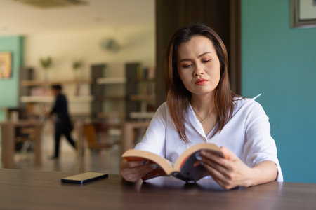 Portrait of beautiful Asian woman sitting in libraryの写真素材