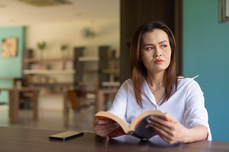 Portrait of beautiful Asian woman sitting in libraryの写真素材