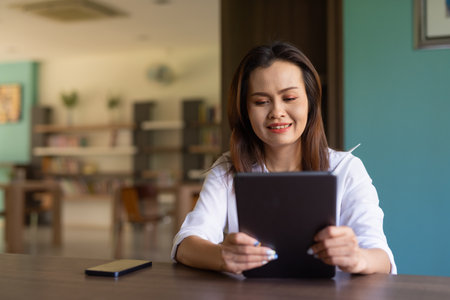 Portrait of beautiful Asian woman sitting in libraryの写真素材