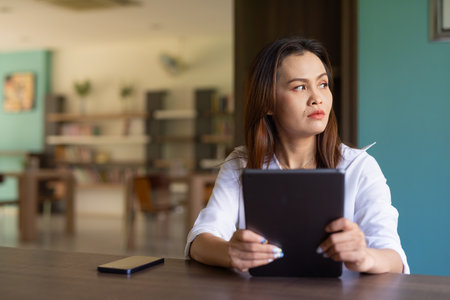 Portrait of beautiful Asian woman sitting in libraryの写真素材