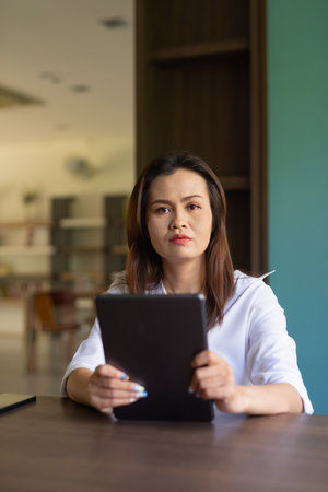 Portrait of beautiful Asian woman sitting in libraryの写真素材