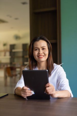 Portrait of beautiful Asian woman sitting in libraryの写真素材