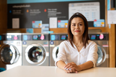 Portrait of beautiful Asian woman sitting in laundry shopの写真素材