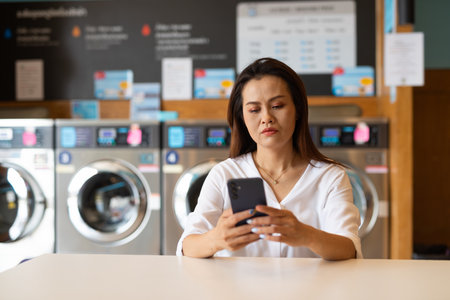Portrait of beautiful Asian woman sitting in laundry shopの写真素材