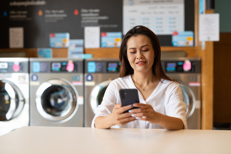 Portrait of beautiful Asian woman sitting in laundry shopの写真素材