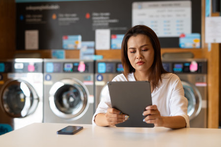 Portrait of beautiful Asian woman sitting in laundry shopの写真素材