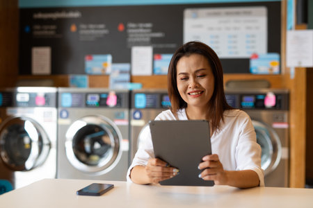 Portrait of beautiful Asian woman sitting in laundry shopの写真素材