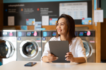 Portrait of beautiful Asian woman sitting in laundry shopの写真素材