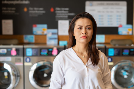 Portrait of beautiful Asian woman sitting in laundry shopの写真素材