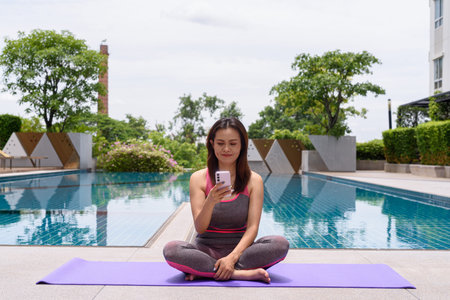 Beautiful Asian woman doing yoga exercise during summer next to swimming poolの写真素材