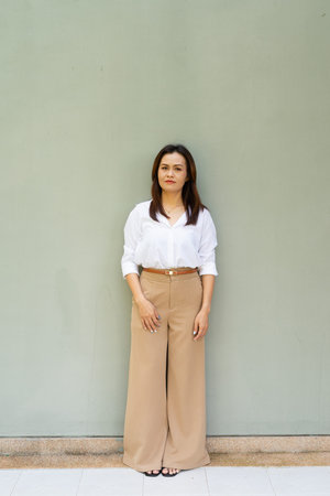 Full length portrait of woman wearing business clothes against plain wall