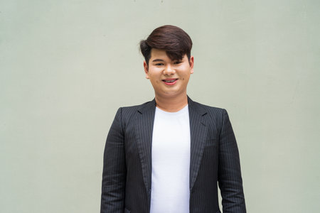 Portrait of cute young gay man against plain wallの写真素材