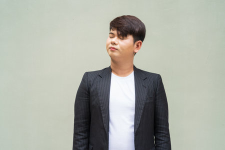 Portrait of cute young gay man against plain wallの写真素材