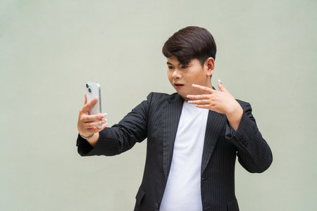 Portrait of cute young gay man against plain wallの写真素材