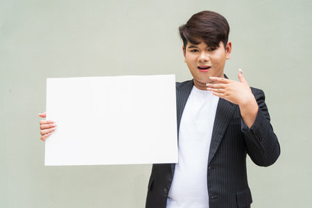 Portrait of cute young gay man against plain wallの写真素材