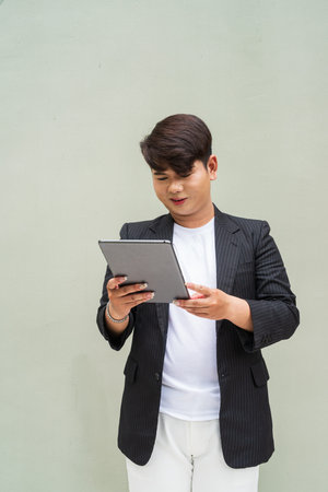 Portrait of cute young gay man against plain wall