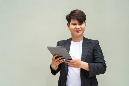 Portrait of cute young gay man against plain wall