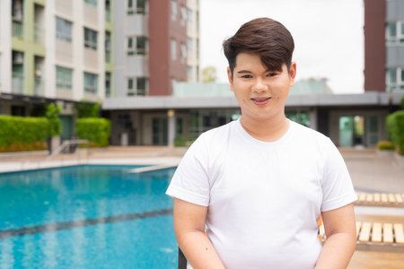 Young cute Asian gay man relaxing next to swimming pool during summer holidayの写真素材