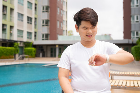 Young cute Asian gay man relaxing next to swimming pool during summer holidayの写真素材