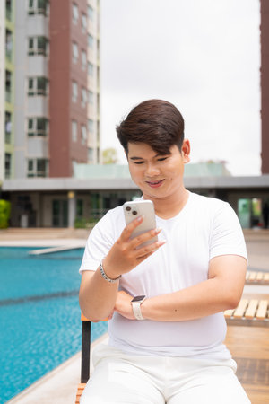 Young cute Asian gay man relaxing next to swimming pool during summer holidayの写真素材