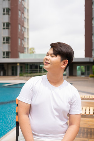 Young cute Asian gay man relaxing next to swimming pool during summer holidayの写真素材