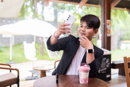 Young cute gay man makeup artist businessman in coffee shop restaurant wearing business clothes