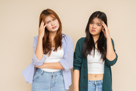 Portrait of two young Asian woman against plain wallの写真素材