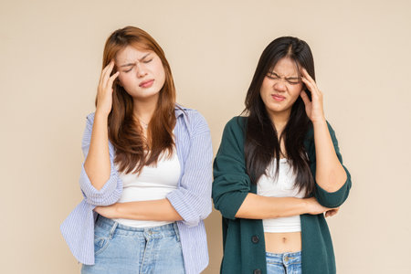 Portrait of two young Asian woman against plain wallの写真素材