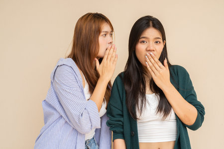 Portrait of two young Asian woman against plain wall