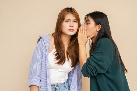 Portrait of two young Asian woman against plain wall