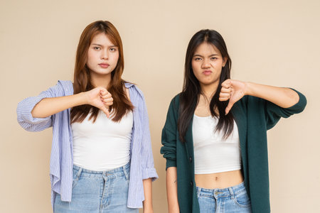 Portrait of two young Asian woman against plain wallの写真素材