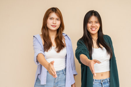 Portrait of two young Asian woman against plain wallの写真素材