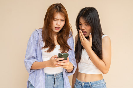 Portrait of two young women against plain wallの写真素材