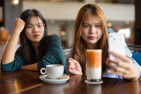 Two young Asian woman sitting together in cafe restaurantの写真素材