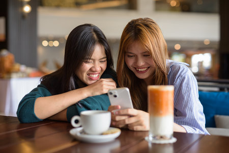 Two young Asian woman sitting together in cafe restaurantの写真素材