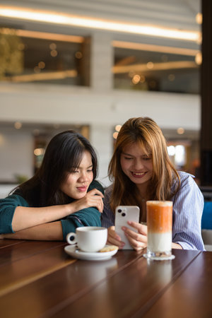 Two young Asian woman sitting together in cafe restaurantの写真素材